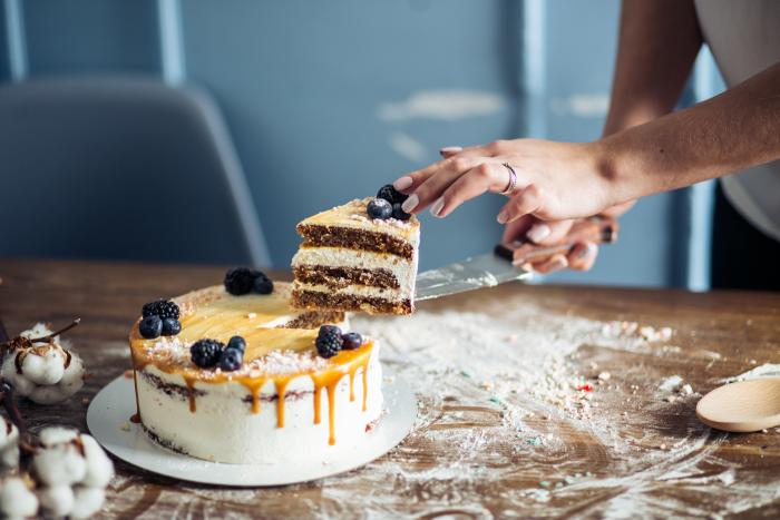 Hands presenting a slice of cake