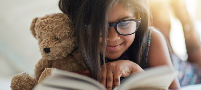 Girl reading book with teddy