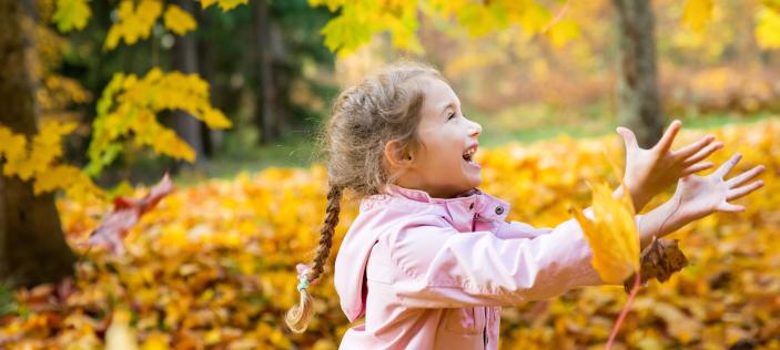 Child playing in autumn leaves 