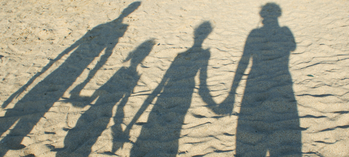 Shadow of family holding hands on the beach 