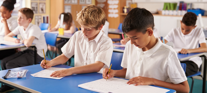 Students writing in books in classroom