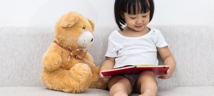 Early Years child reading to teddy
