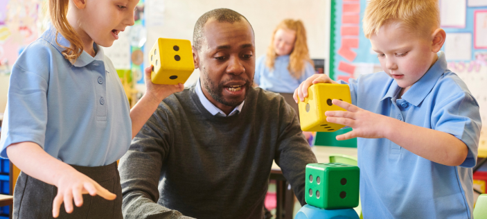 Teacher with students who are playing with extra large dice