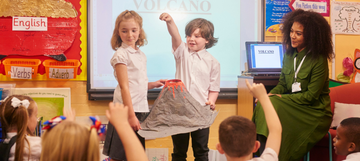 Children displaying model volcano in-front of class