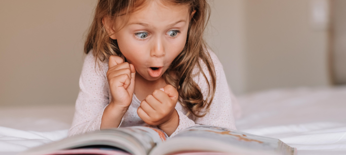 Girl reading a book. She looks excited.
