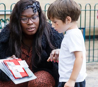woman of colour showing small child a book