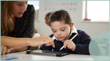 boy using an ipad with teacher