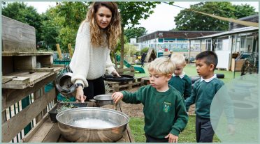 female practitioner with early years children outdoors