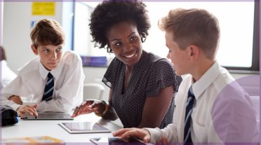 female teacher of colour with 2 male pupils with ipads