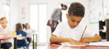 Don't forget your full stops! Child writing at desk with pencil